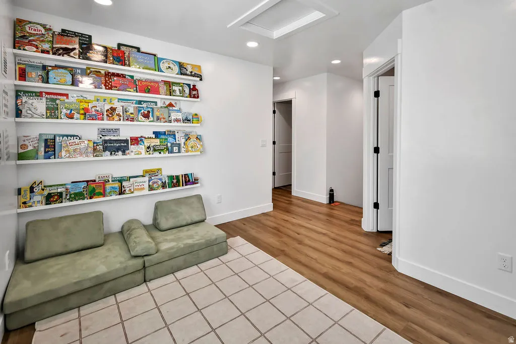 Bright interior space featuring a wall of built-in shelving, wood-finish flooring, recessed lighting, and white baseboards