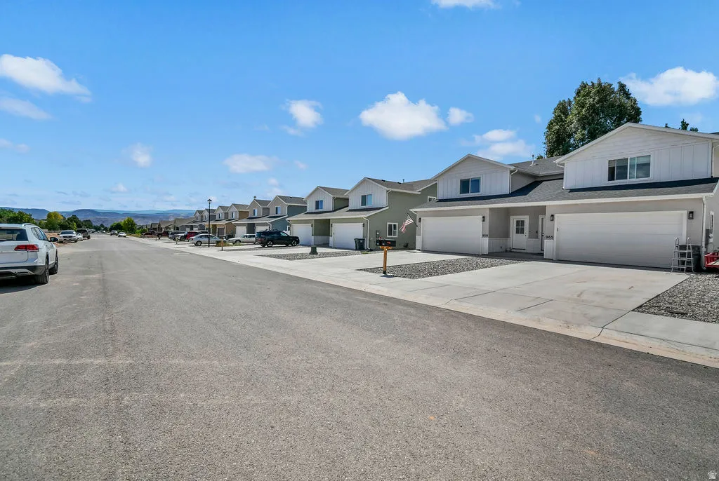 Contemporary residential streetscape featuring two-story townhomes with light grey siding and white trim