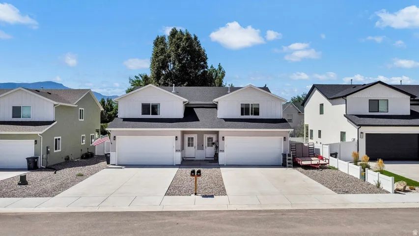 Modern duplex building with white siding and dark roofing
