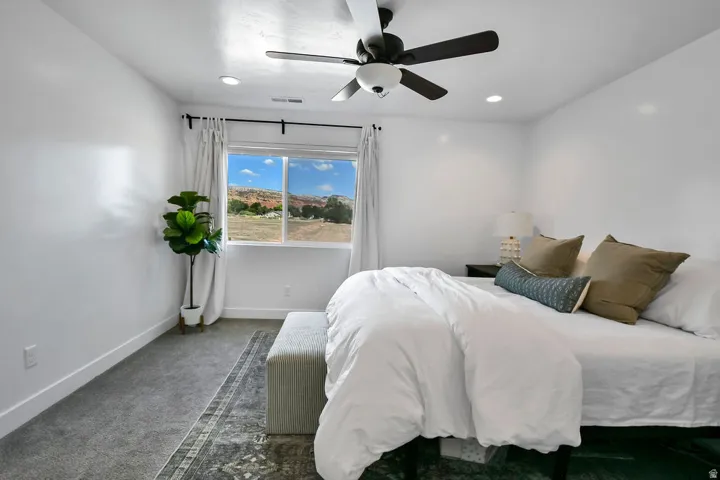 Carpeted room featuring a ceiling fan with integrated lighting, recessed lighting, and a window with white trim