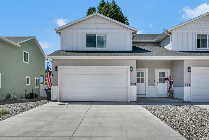 Two-story townhouse exterior with a light stucco finish and white board-and-batten siding