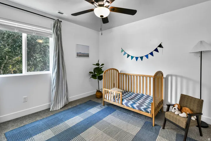 Bright room with a large window, a ceiling fan, and carpeted flooring