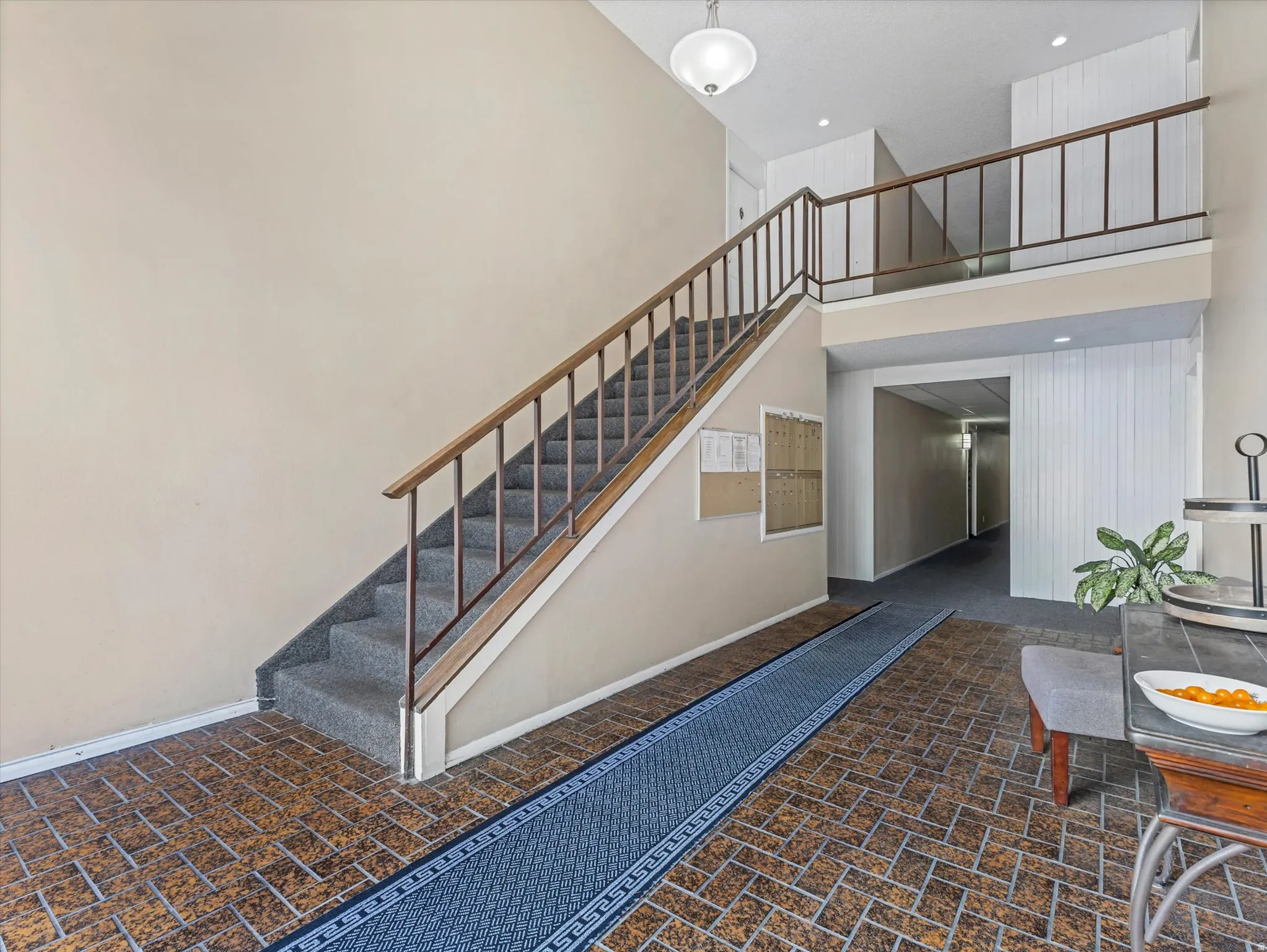 Entryway featuring a staircase with carpeted treads and wood-finish railing, a second-story landing with matching railing, and brick-patterned flooring
