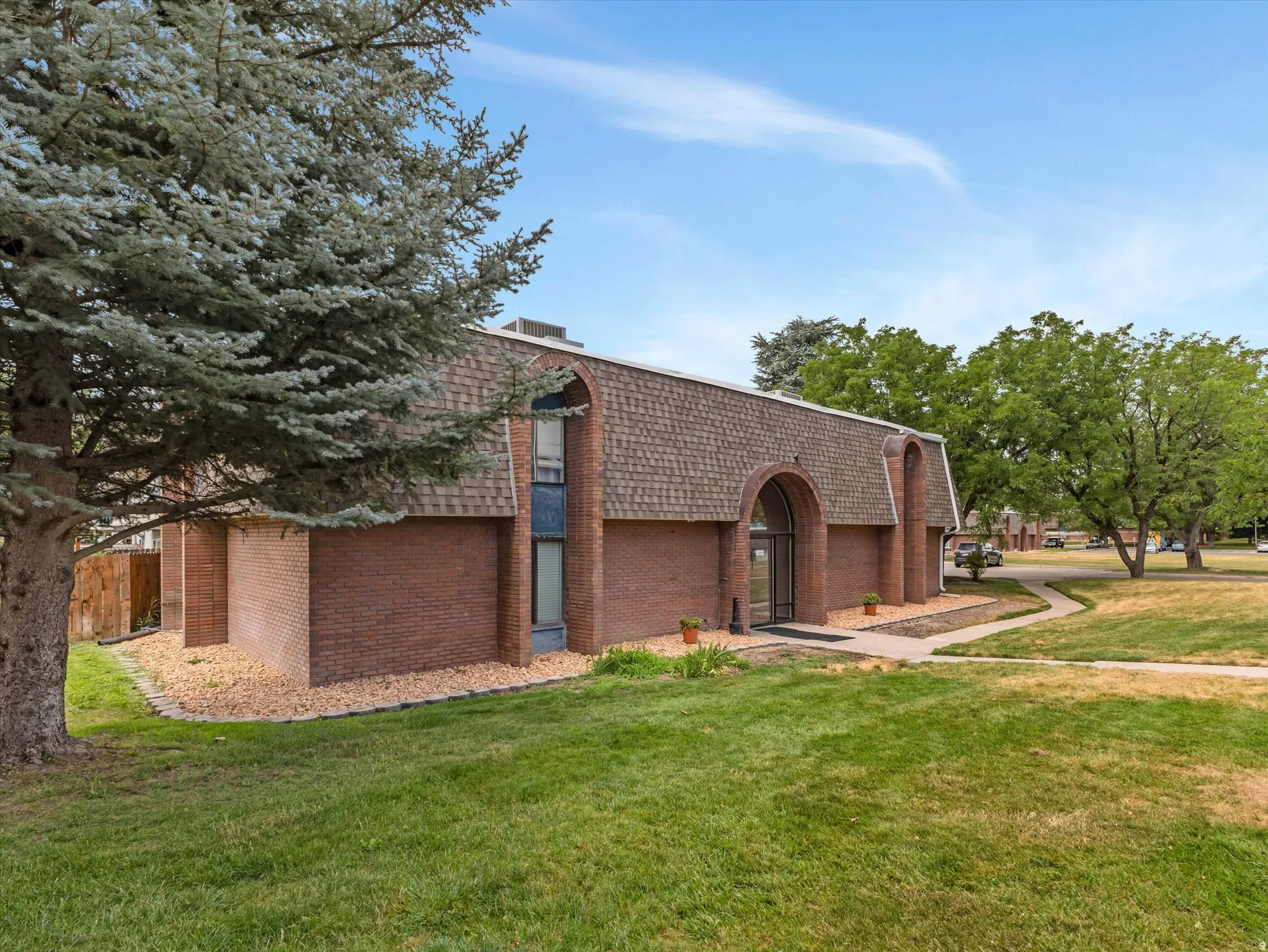 Brick exterior with a prominent arched entry and a shingled gambrel roofline