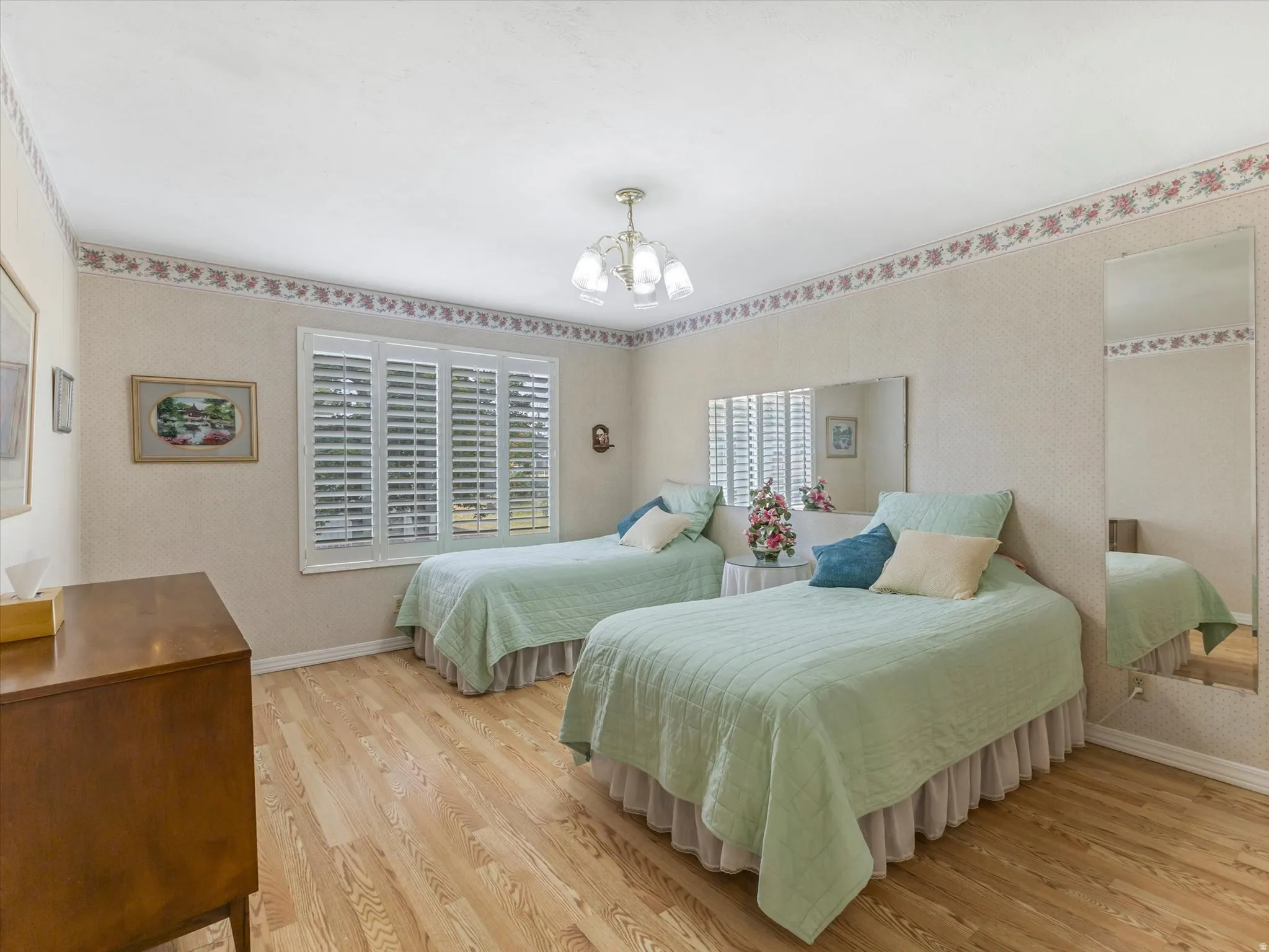 Room featuring wood-finish flooring, a multi-pane window with louvered shutters, and a ceiling-mounted light fixture