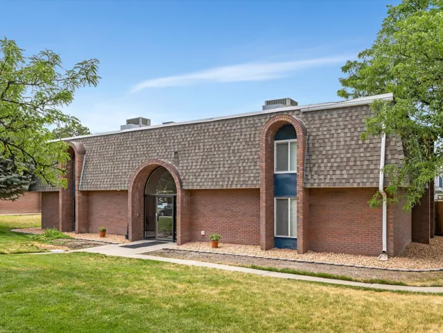 Brick exterior with a mansard roof, arched entryway, and mature landscaping