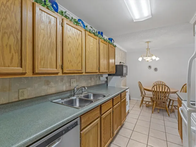 Kitchen featuring wood cabinetry, a double basin stainless steel sink, a built-in dishwasher, and a microwave
