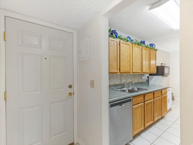 Entryway with a paneled white door, gold-tone hardware, and an adjacent kitchen area