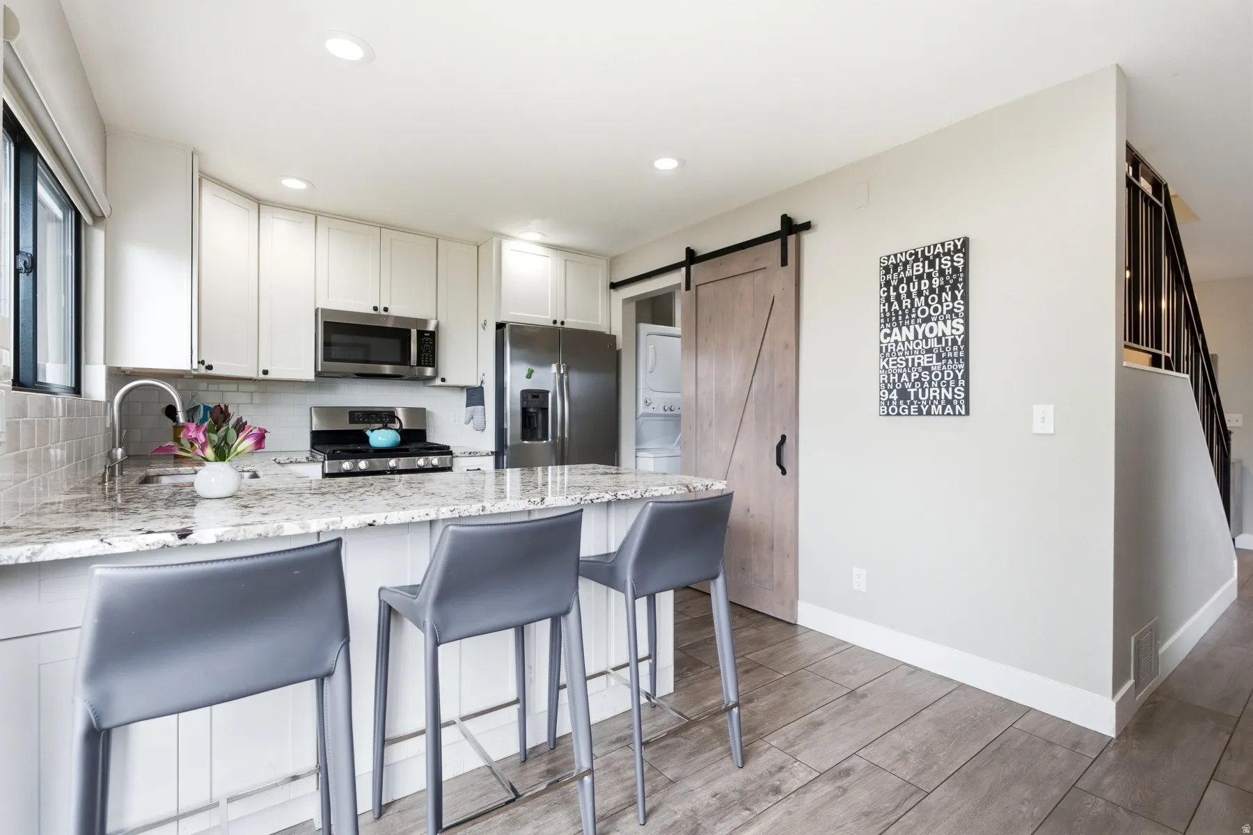 Contemporary kitchen featuring light wood-finish flooring, white cabinetry, and stainless steel appliances