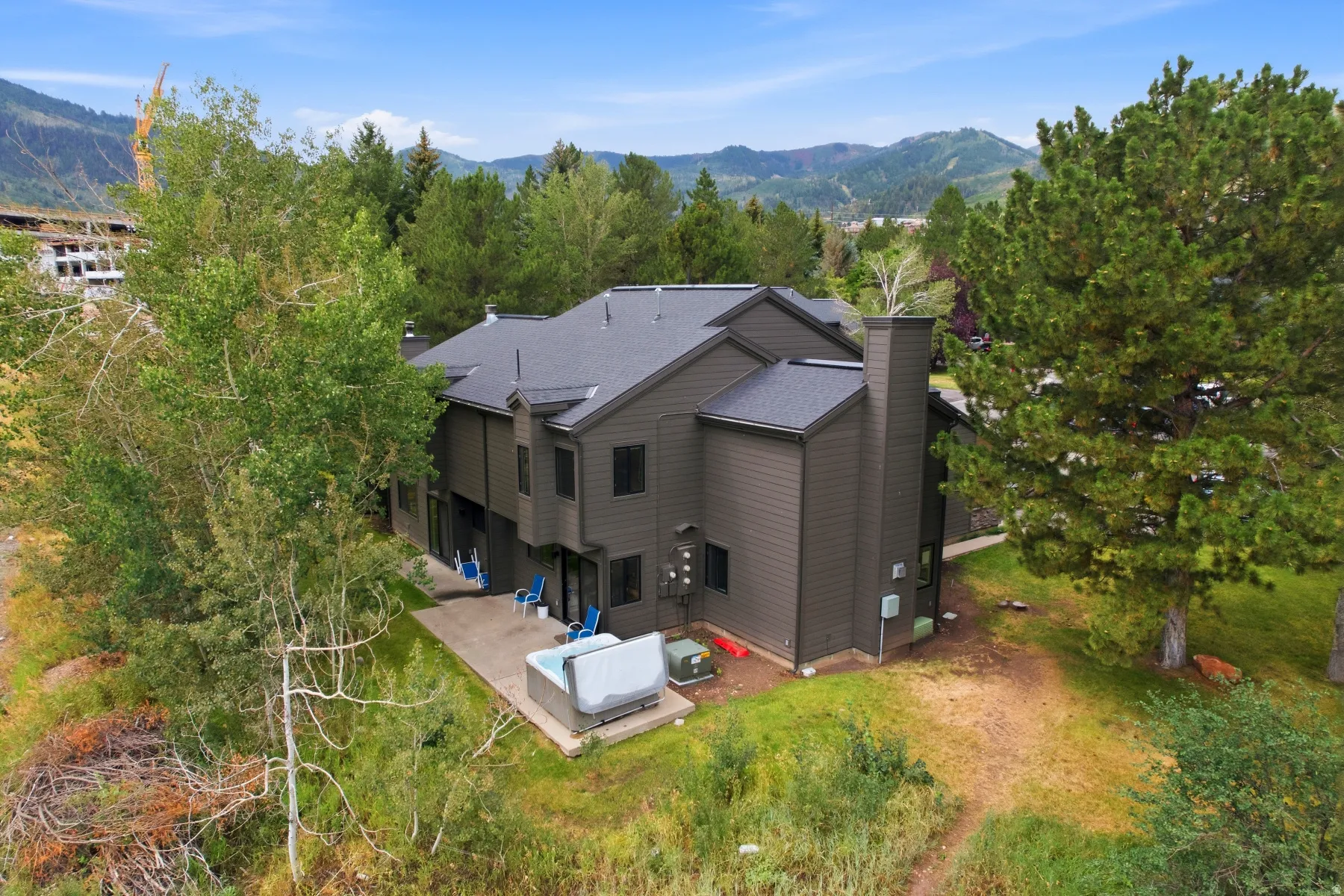 Multi-level residence featuring dark siding and a dark shingle roof
