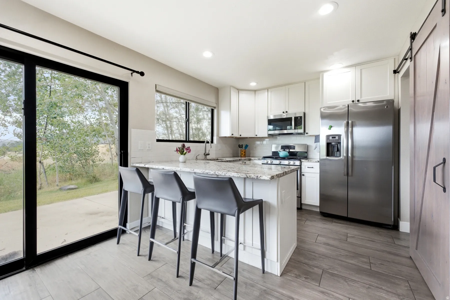 Kitchen featuring a central island with countertop seating, white cabinetry, stainless steel appliances, and a wood-finish flooring