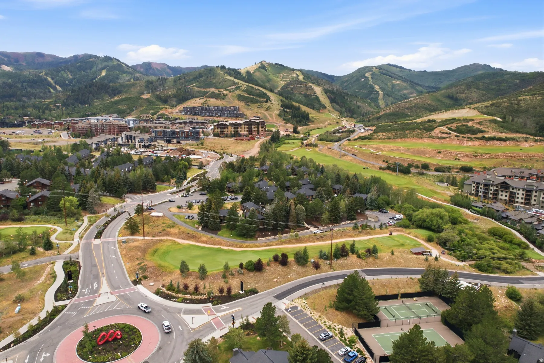 Expansive mountain landscape featuring varied terrain, a ski resort with visible trails, and a golf course