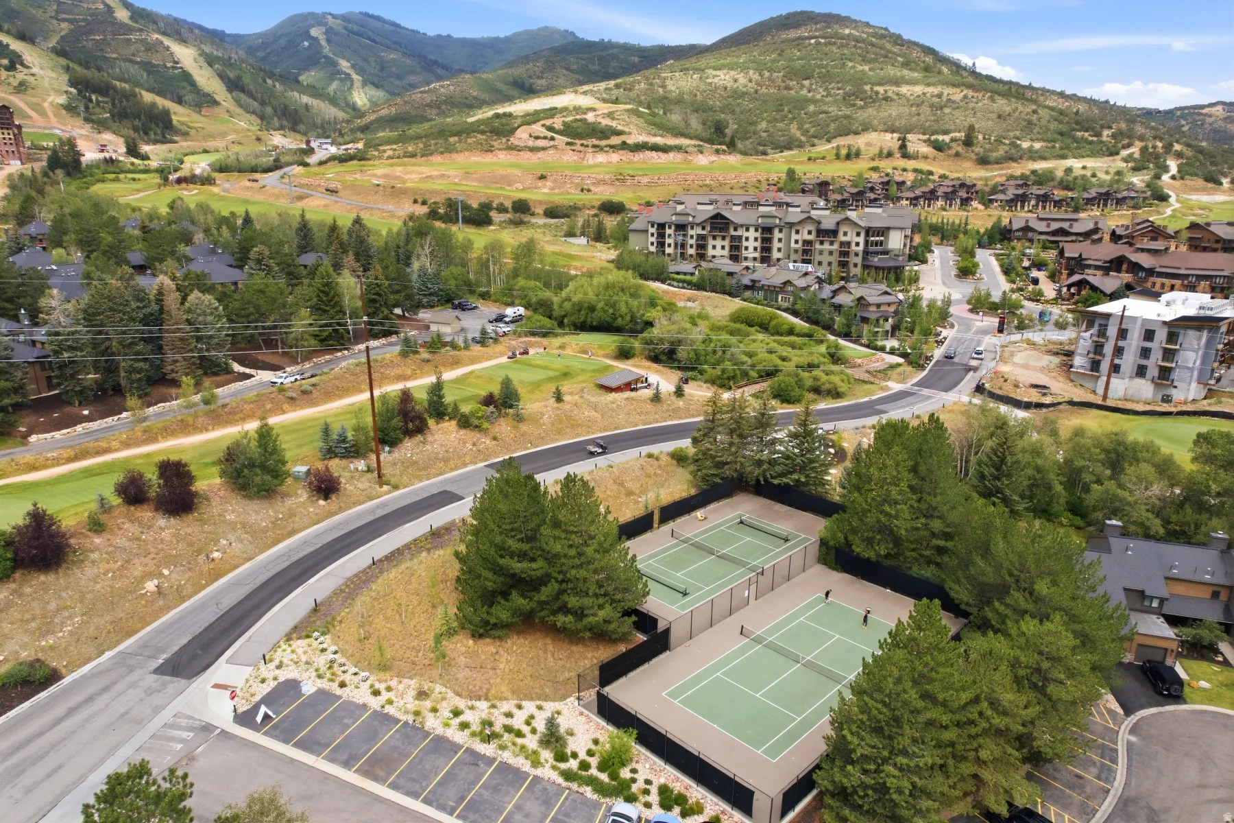 Two tennis courts featuring green playing surfaces and perimeter fencing