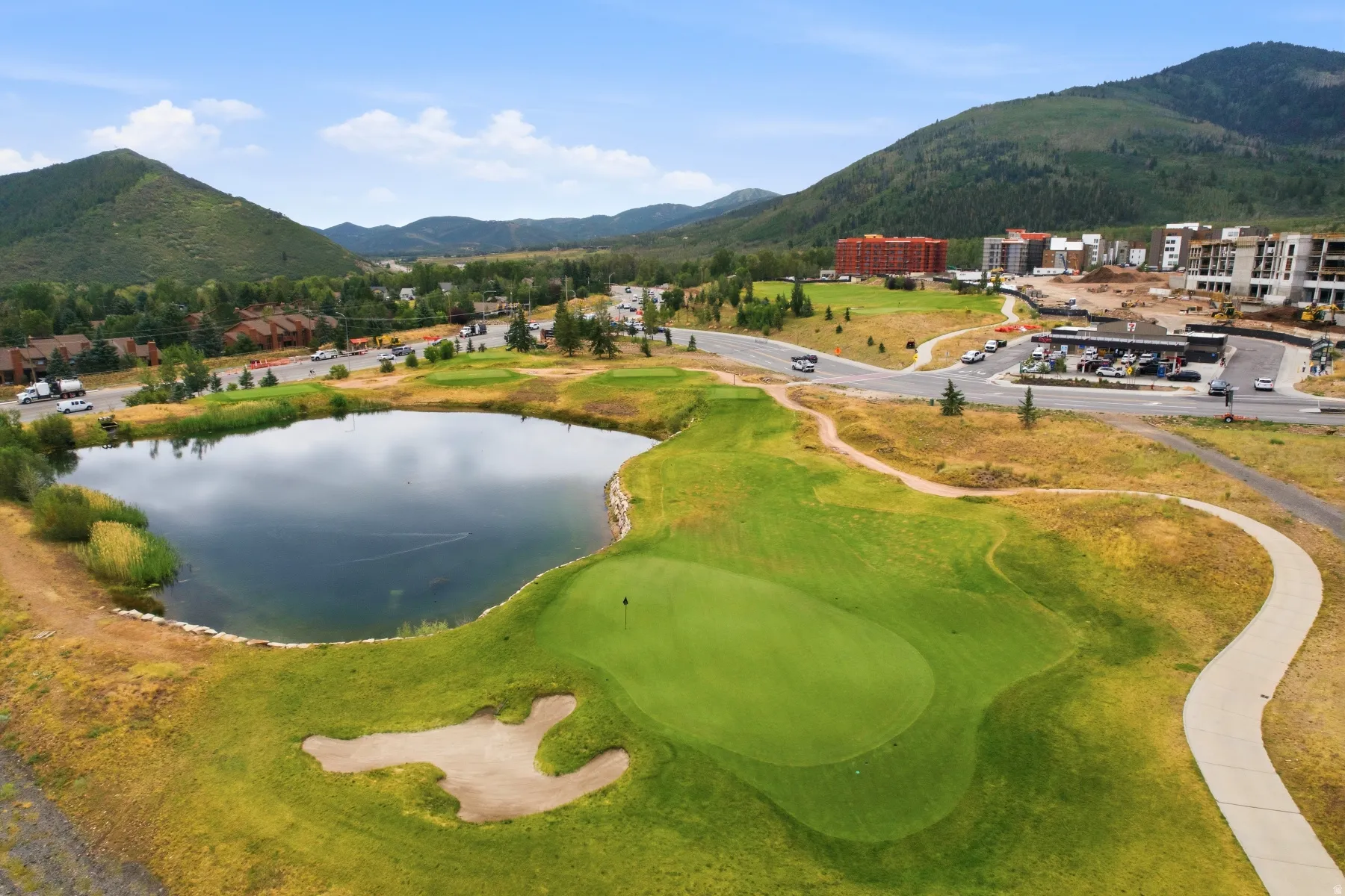 Expansive golf course featuring a manicured putting green, sand trap, and a water hazard
