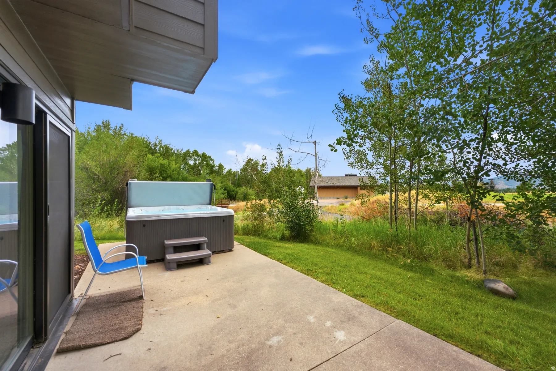 Private patio featuring a built-in hot tub, concrete paving, and a sliding glass door
