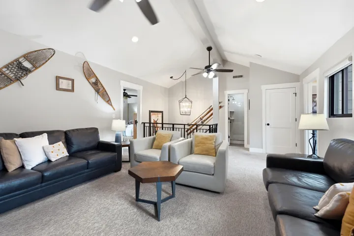 Spacious living area featuring vaulted ceilings, recessed lighting, and soft gray carpeting