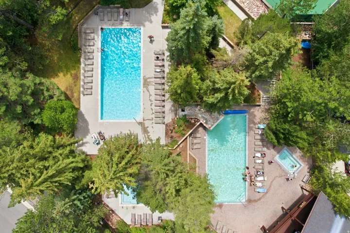 Two sparkling swimming pools with surrounding lounge areas and a separate spa