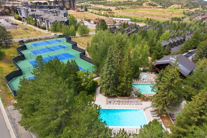 Extensive recreational amenities featuring four tennis courts, two swimming pools, and a spa, all surrounded by mature trees