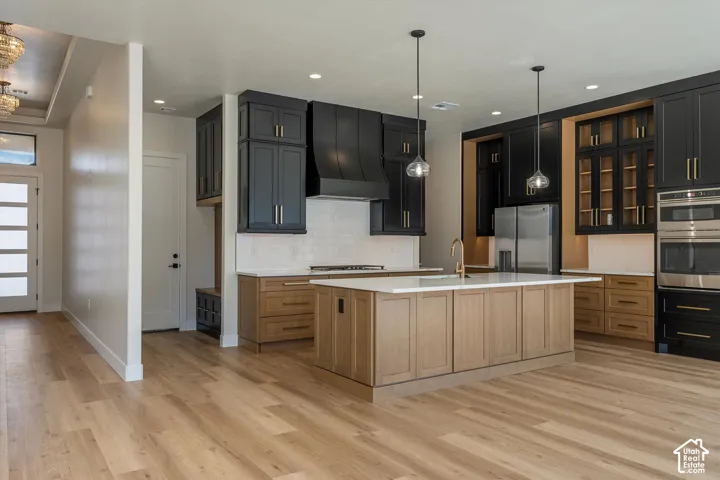 Gourmet kitchen with black and wood-finish cabinetry, white subway tile backsplash, stainless steel appliances, and a central island with a solid surface countertop