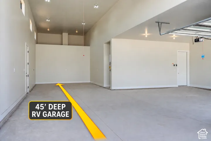 Spacious garage with high ceilings, recessed lighting, concrete flooring, and an overhead garage door