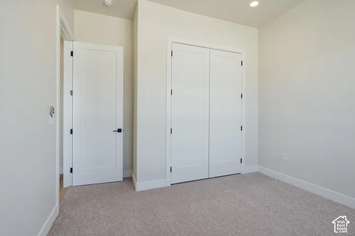 Plush carpeting, recessed ceiling lighting, and white interior doors with matte black hardware