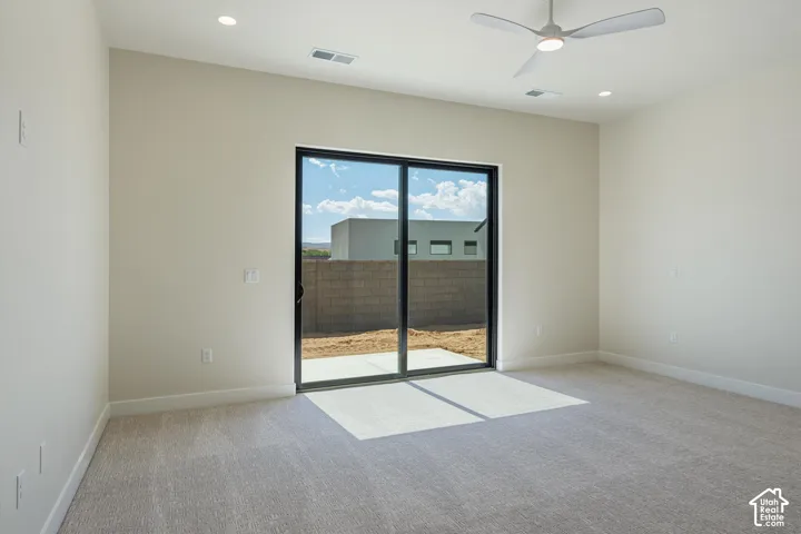 Recessed ceiling lighting, a modern ceiling fan, light-toned carpeting, and a sliding glass door