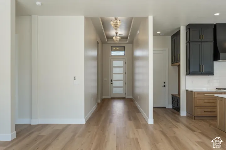 Wood-finish flooring throughout, recessed ceiling with decorative lighting, and a modern entry door with frosted glass panels