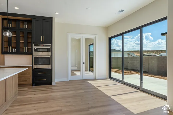 Gourmet kitchen with built-in stainless steel appliances, two-tone cabinetry, and a quartz-surfaced island