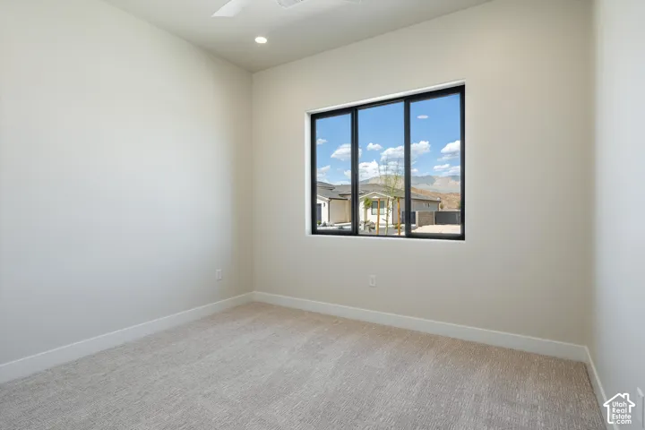 Carpeted flooring, recessed lighting, ceiling fan, and a large multi-pane window with black framing