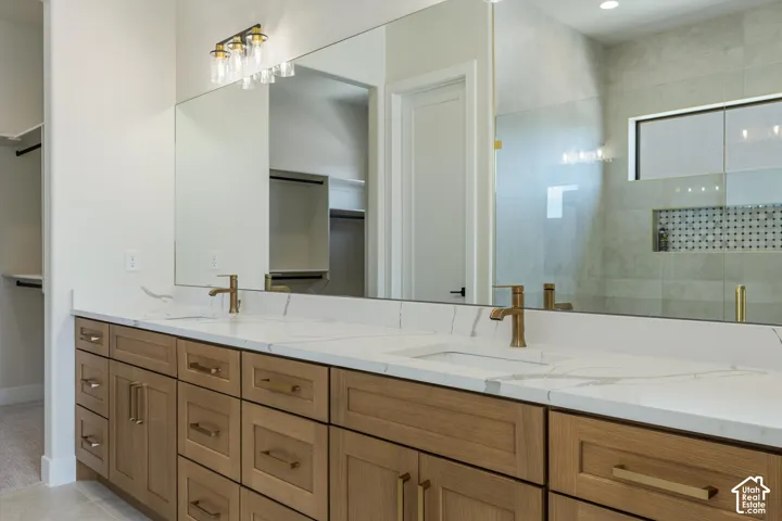 Double vanity with wood-finish cabinetry, white countertops, and brass-finish hardware