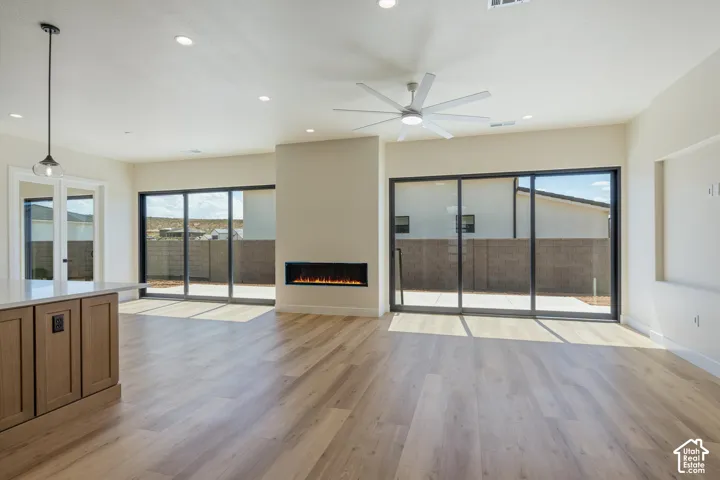 Wood-finish flooring throughout, featuring a modern built-in fireplace, multiple sliding glass doors, and recessed lighting