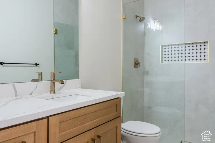 Wood-finish vanity with a quartz countertop, integrated rectangular sink, and gold-tone faucet