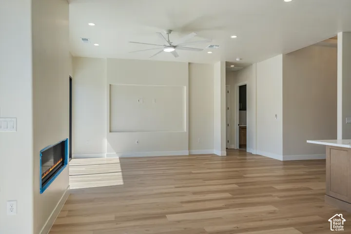 Wood-finish flooring throughout, recessed lighting, ceiling fan, built-in media niche, and an integrated fireplace