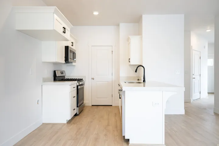 Kitchen with upgraded white cabinets, stainless steel appliances, a pantry, and a peninsula
