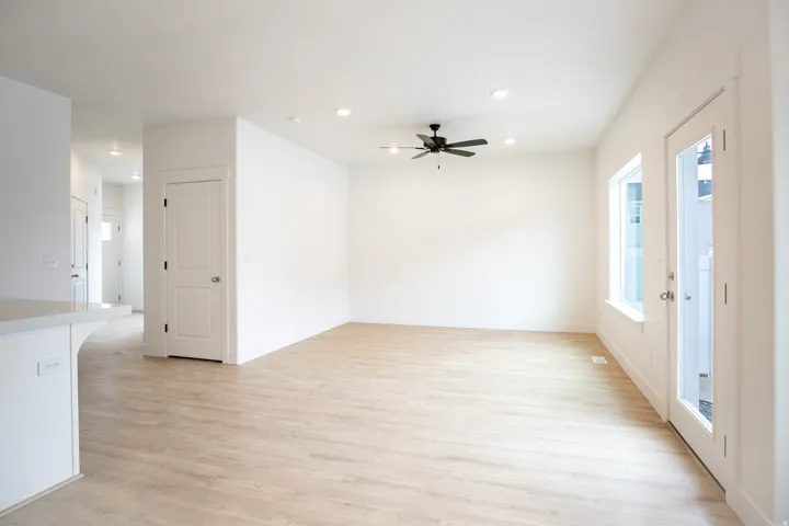 Spacious family room featuring light wood laminate flooring, recessed lighting, and a ceiling fan