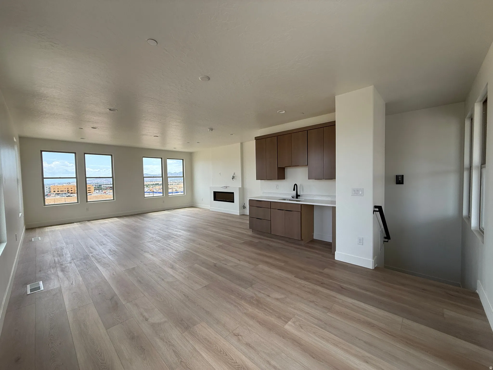 Expansive open-concept living area featuring light wood-finish flooring, recessed lighting, and multiple windows