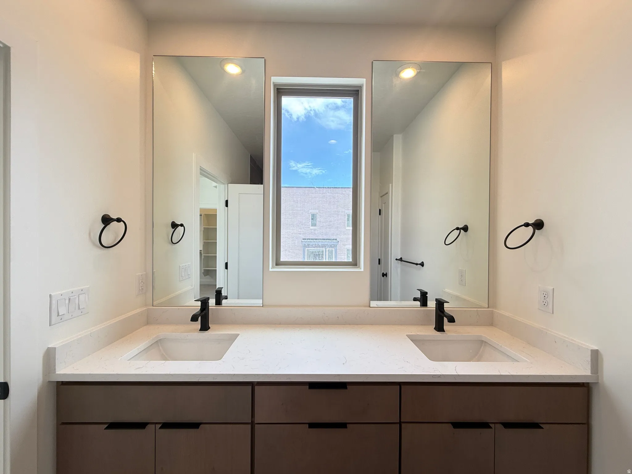 Dual vanities featuring undermount sinks, stone countertops, and matte black fixtures