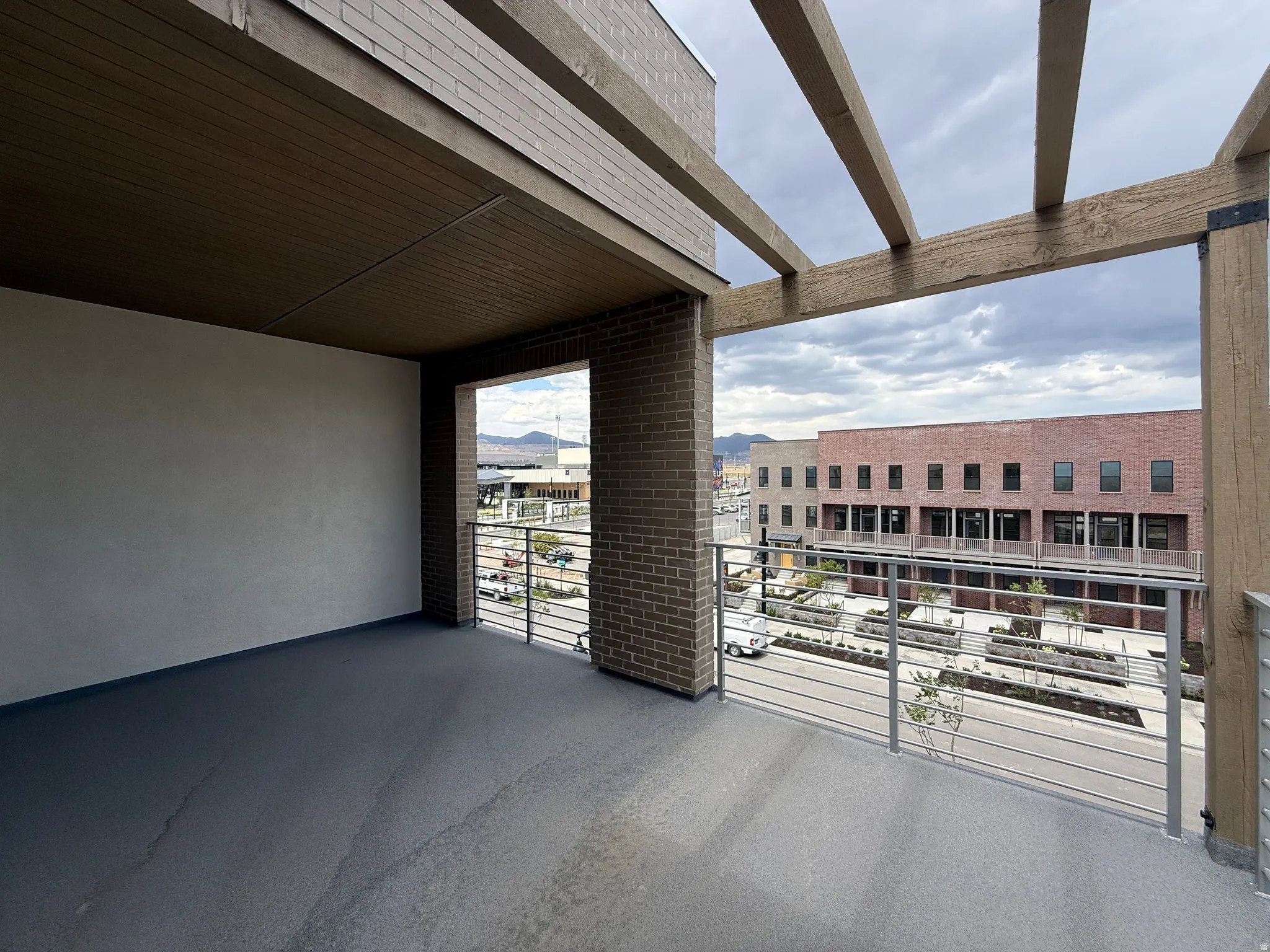 Covered outdoor patio featuring a slat wood-finish ceiling, brick wall, and dark gray flooring