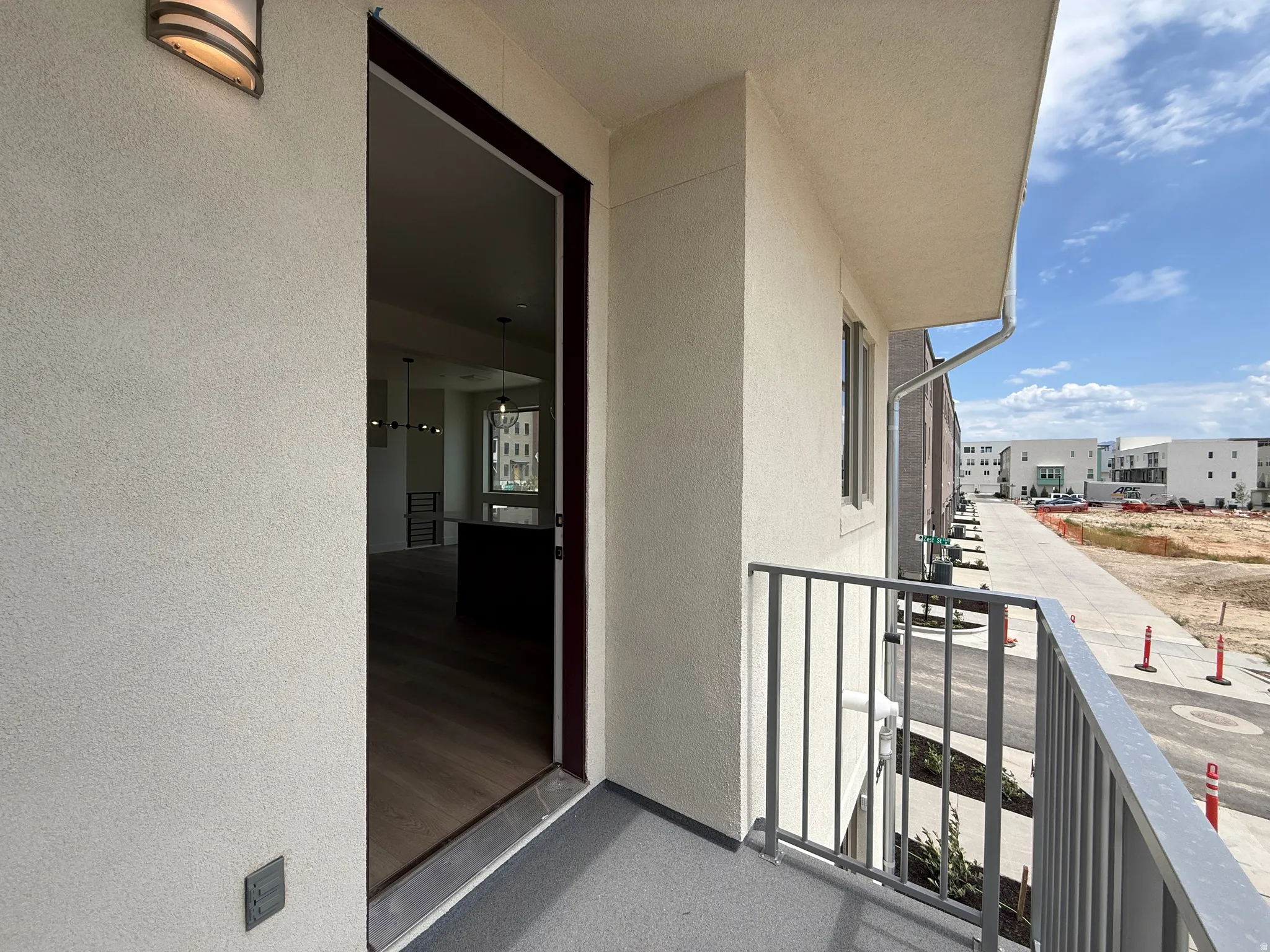 Balcony area featuring a gray metal railing, stucco exterior, and an outdoor wall sconce