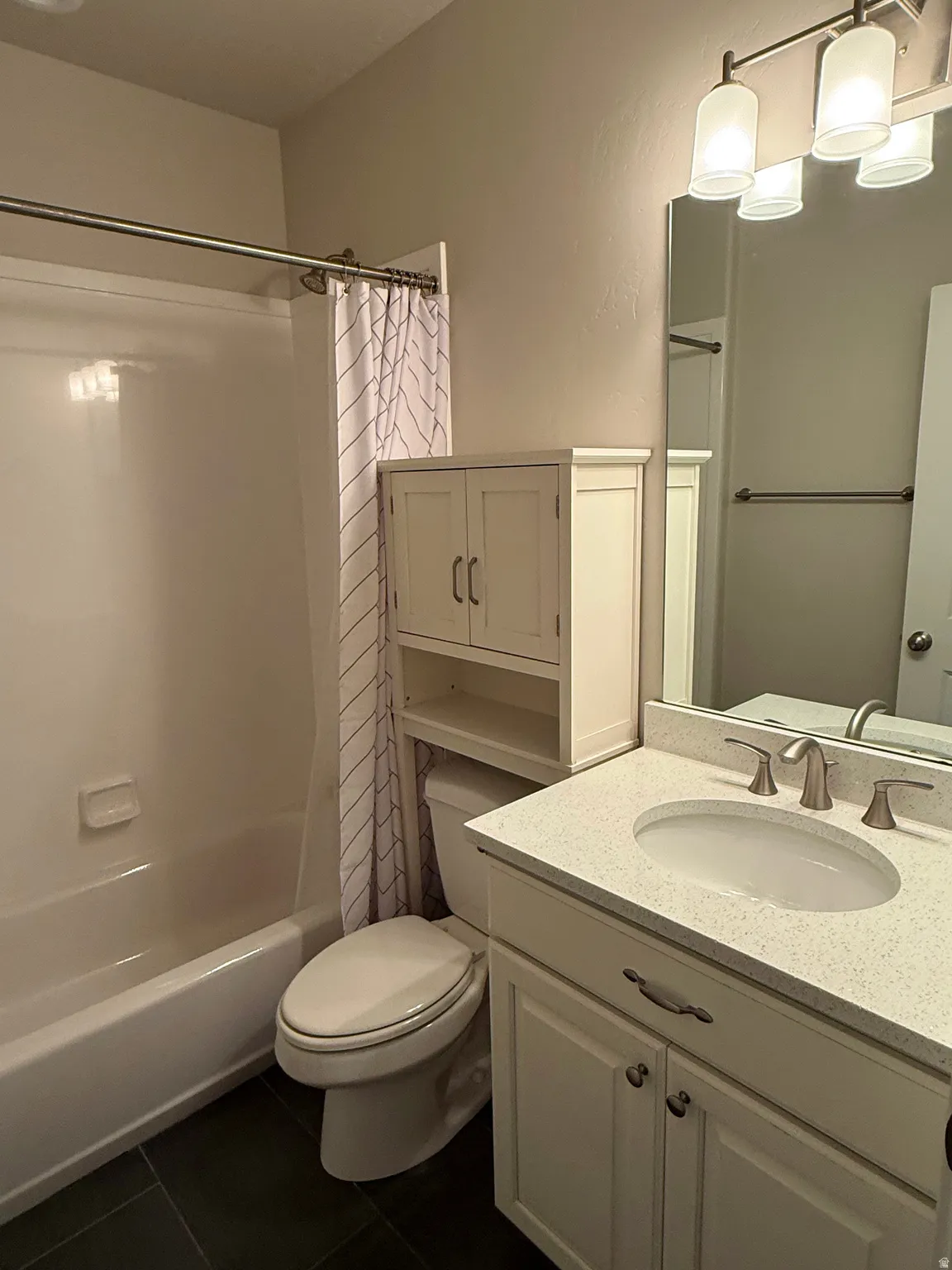 Bathroom featuring a white vanity with a speckled countertop, a white toilet, and a white tub with shower