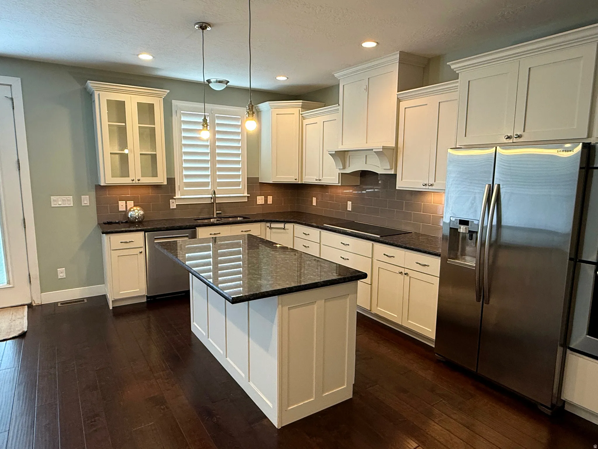 Gourmet kitchen featuring a central island, dark granite countertops, stainless steel appliances, and abundant white cabinetry with crown molding