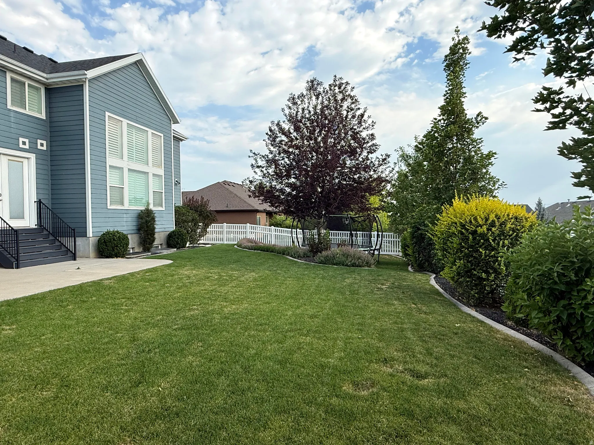 Expansive lawn area featuring mature trees and established landscaping