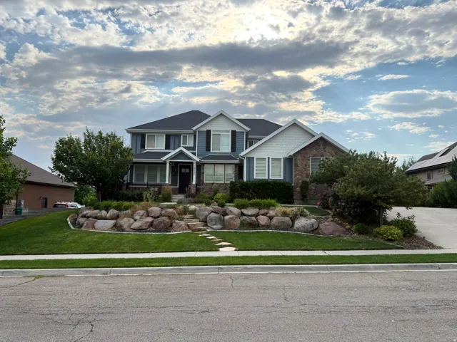 Multi-level residential exterior featuring blue siding, white trim, and stone accents