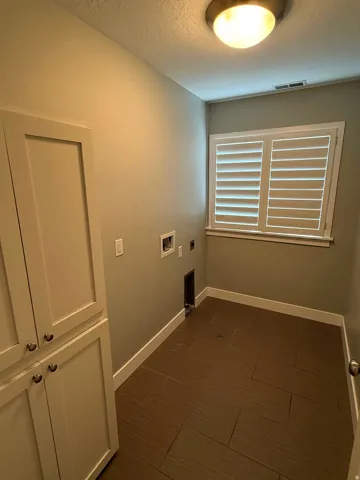 Dedicated utility space featuring built-in cabinetry, wood-look tile flooring, and window shutters