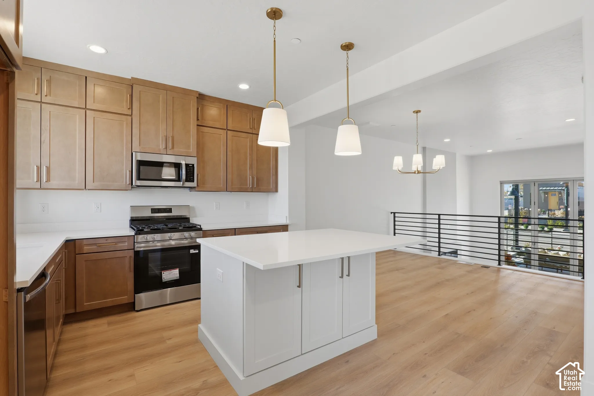 Kitchen featuring wood-finish cabinetry, quartz countertops, a central island with storage, stainless steel appliances, and wood-finish flooring