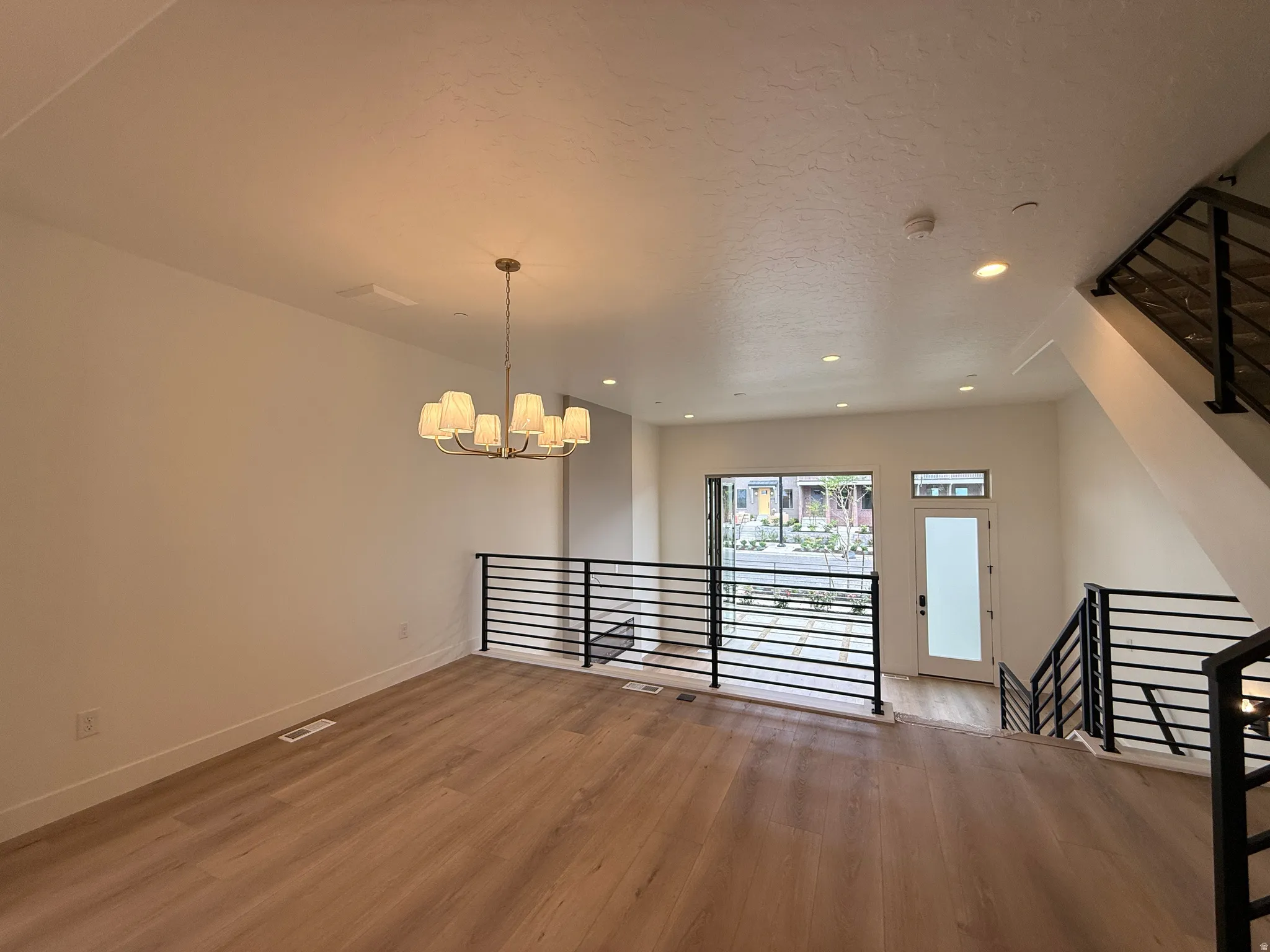 Open-concept living space featuring wood-finish flooring, a modern chandelier, and recessed lighting