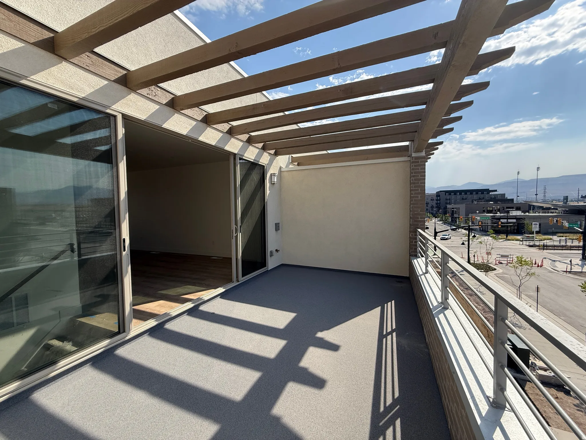 Expansive outdoor terrace featuring a slatted wood pergola, light gray outdoor carpeting, and metal railings