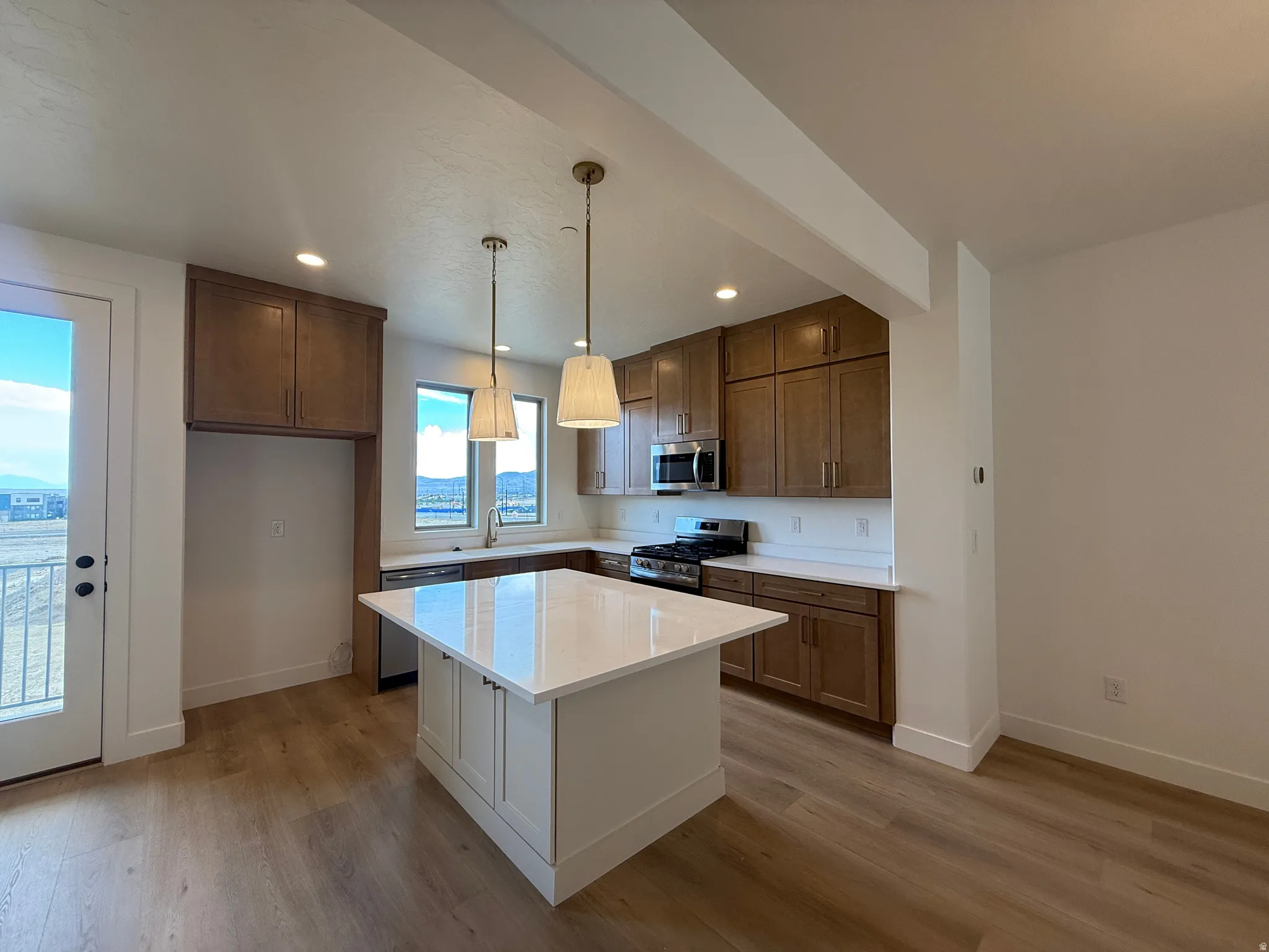 Kitchen featuring a central island with white countertop, recessed lighting, and pendant fixtures