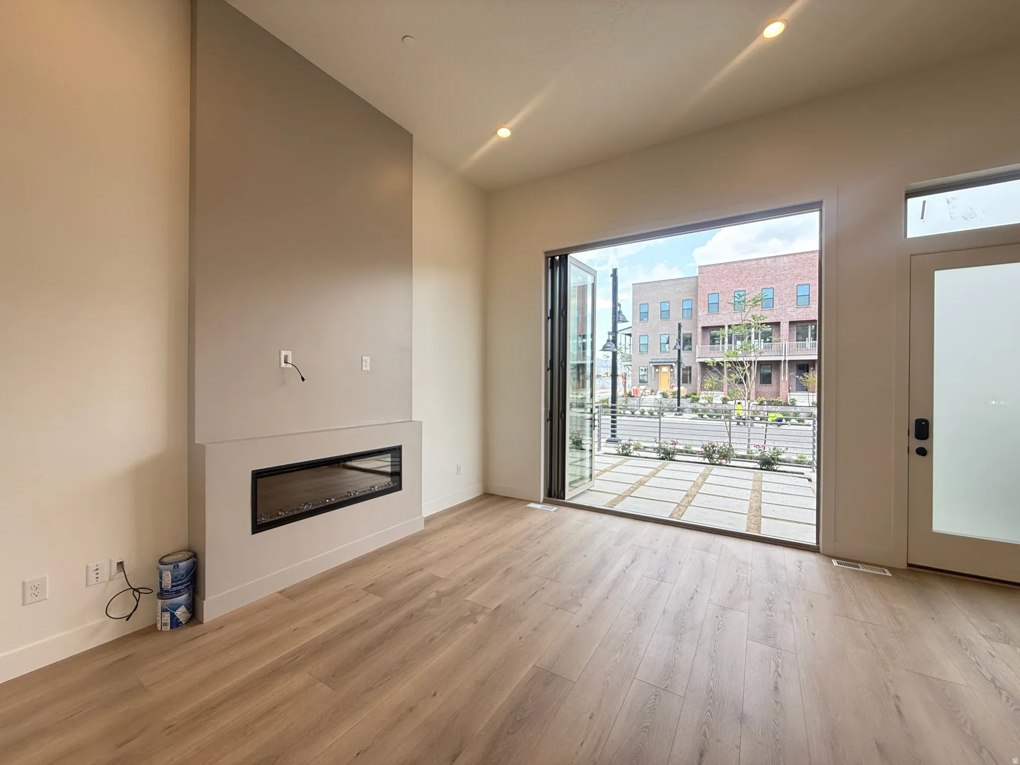 Spacious interior featuring wood-finish flooring, high ceilings with recessed lighting, and a linear electric fireplace