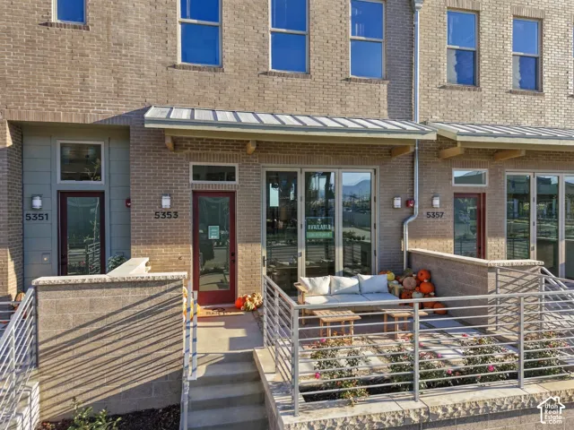 Brick exterior featuring metal awnings, multi-panel glass doors, concrete terraces, and horizontal metal railing